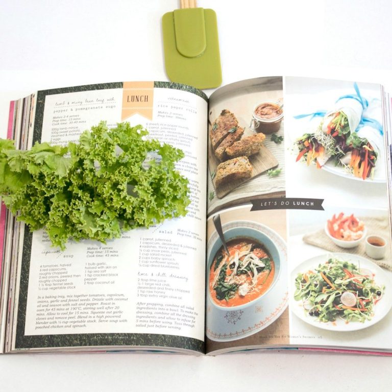 Foto von SOCIAL.CUT von Unsplash Ein offenes Kochbuch mit verschiedenen Rezepten und einem Bund frischer Petersilie.